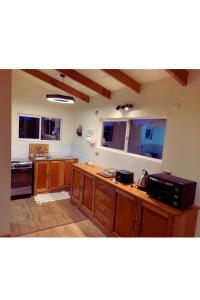 a large kitchen with wooden cabinets and windows at El Tambo del Anakiri in Los Muermos