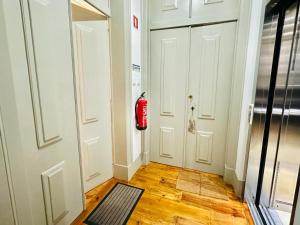 um corredor com duas portas brancas e um extintor de incêndio vermelho em Varandas do Marquês em Lisboa