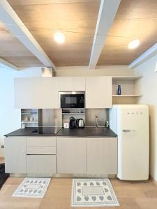 a kitchen with white cabinets and a refrigerator at Le Petit Chalet Limone in Limone Piemonte