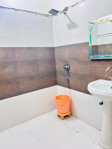 ein Badezimmer mit einem orangenen Eimer neben einem Waschbecken in der Unterkunft Sunrise hotel in Jalandhar