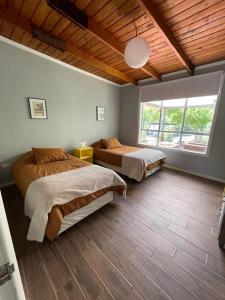 1 dormitorio con 2 camas y ventana grande en Agradable casa con Tina de agua Caliente y Piscina, en Quillón