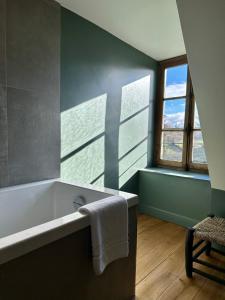 a bathroom with a bath tub and a window at Le Manoir du Rigouneix au coeur de la nature, calme-sauna-dîner maison in Saint-Angel