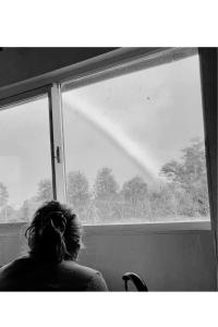 a woman sitting in a chair looking out of a window at El Tambo del Anakiri in Los Muermos