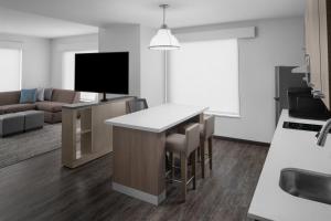 uma cozinha e sala de estar com um bar e uma televisão em Hyatt House Lansing-University Area em Lansing