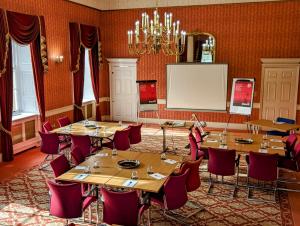 einen Konferenzraum mit Tischen, Stühlen und einem Whiteboard in der Unterkunft Hitchin Priory Hotel in Hitchin