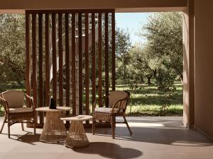a patio with two chairs and a table and two tables at Hora Ionica Villa, Private Pool & 10acre GreenLand, By ThinkVilla in Koukounariá +33 photos