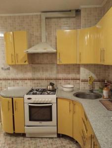 una cucina con armadi gialli, piano cottura e lavandino di Однокомнатная квартира в центре города, Панфилова 80, Алматы a Almaty