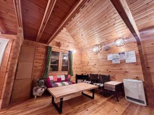 a wooden cabin with a table and a couch at Aki in Hakuba