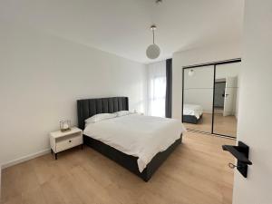 a white bedroom with a large bed and a mirror at Exit Aparthotel in Floreşti