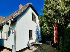 a small white house with a table and an umbrella at Haus am Berg 2 in Neuenkirchen