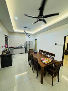 une salle à manger avec une table, des chaises et un ventilateur de plafond dans l'établissement Maxwell Merpati Taiping Homestay, à Kamunting