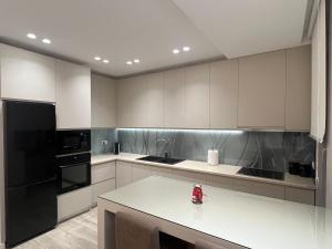 a kitchen with white cabinets and black appliances at Rei’s Apartment Korce in Korçë