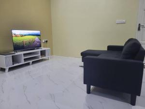 sala de estar con sofá negro y TV en Veyodhoshuge, S.Feydhoo, Addu city, en Feydhoo