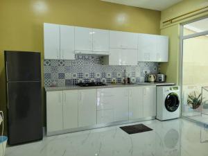 cocina con armarios blancos, lavadora y secadora en Veyodhoshuge, S.Feydhoo, Addu city, en Feydhoo