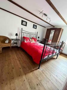 1 dormitorio con 1 cama con sábanas rojas y suelo de madera en Maison 6 personnes avec piscine, en Le Conquet