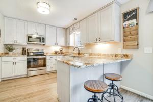 a kitchen with white cabinets and a counter with stools at Bright Helen Cottage Walk to Town! in Helen
