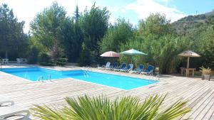 a large swimming pool with chairs and umbrellas at Hôtel Sous l'Olivier in Buis-les-Baronnies