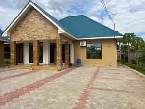 una pequeña casa con techo verde en J & S LUGALLA HOUSE, en Dar es Salaam