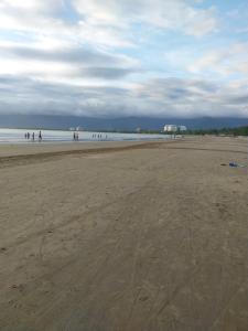 un grupo de personas caminando por la playa en Kitnet Indaiá en Bertioga