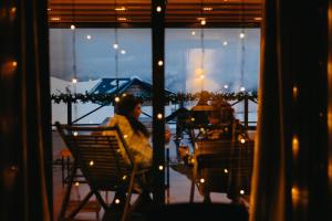 una mujer sentada en una silla mirando por una ventana en Alpina Hotel, en Gudauri