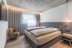 a bedroom with a large bed and a chair at Köfele Lodge Agnes in Parcines