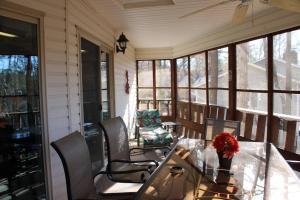 a screened in porch with a glass table and chairs at Aunt Pattie's Lake House in Fairfield Bay