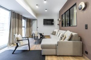 uma sala de estar com um sofá e uma televisão em HSH Parmentier-Couronnes I Appartement Design 6P-2BR em Paris