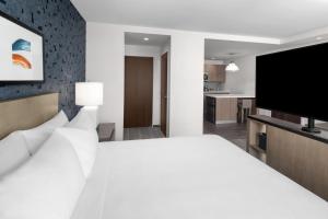 兰辛Hyatt House Lansing-University Area的卧室里有一张白色的床和一台平板电视