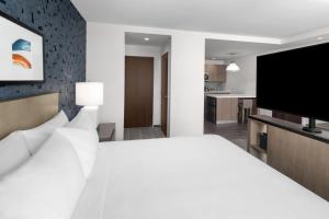 um quarto com uma cama branca e uma televisão de ecrã plano em Hyatt House Lansing-University Area em Lansing