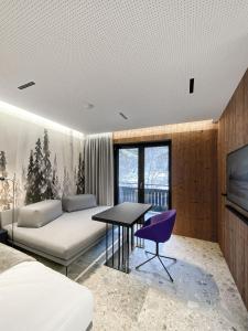 een slaapkamer met een bed en een tafel en een televisie bij LOFT 27 Saalbach in Saalbach Hinterglemm
