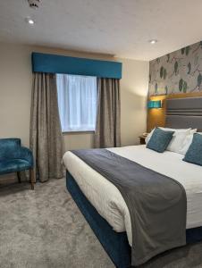 a hotel room with a large bed and a window at The Briar Court Hotel in Huddersfield