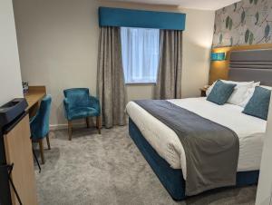 Habitación de hotel con cama y silla en The Briar Court Hotel, en Huddersfield