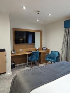 a bedroom with a desk with a television and two chairs at The Briar Court Hotel in Huddersfield