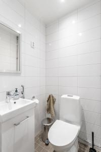La salle de bains blanche est pourvue de toilettes et d'un lavabo. dans l'établissement Cozy, spacious and calm city home - top location, à Helsinki