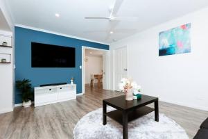een woonkamer met een blauwe accentmuur en een tafel bij Lovely House in Smithfield in Smithfield