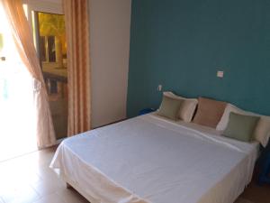 1 dormitorio con cama blanca y pared verde en Hôtel Colibri, en Niaga
