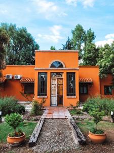una casa arancione con una porta in un cortile di Finca La Saucina Casa de Campo a Tunuyán