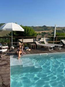 a woman is sitting next to a swimming pool at Relais B&B Betty Bike in Sasso Feltrio