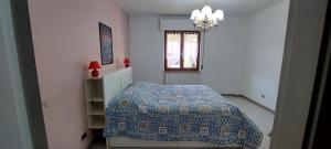 een slaapkamer met een bed, een raam en een kroonluchter bij Rosa's House in Sarnano