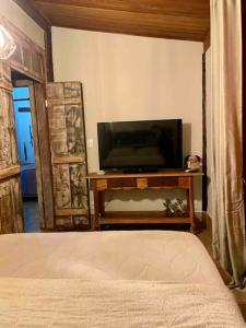 Casa Portal Sagrado Matutu- Aiuruoca MG في أيوريوكا: غرفة نوم مع تلفزيون بشاشة مسطحة وسرير