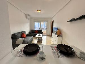 ein Wohnzimmer mit einem Tisch mit Tellern darauf in der Unterkunft Homely Apartments Vitoria in Torrevieja