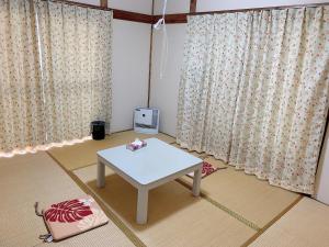 Tokyo Kamakura House في طوكيو: غرفة معيشة مع طاولة بيضاء وستائر
