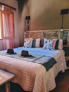 Dos camas en una habitación con sombreros encima. en Finca La Saucina Casa de Campo en Tunuyán