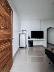 Zimmer mit einem Kühlschrank, einem TV und einer Tür in der Unterkunft L.C. Apartments in Nathon Bay