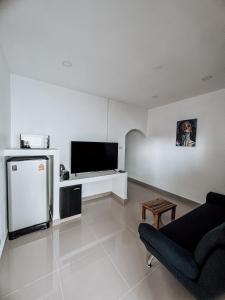 ein weißes Wohnzimmer mit einem TV und einem Sofa in der Unterkunft L.C. Apartments in Nathon Bay