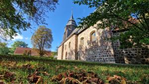 an old stone church with a steeple in the grass at Gästehaus Wilsickow in Lübbenow