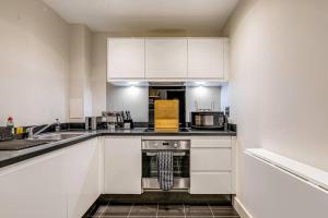 a kitchen with white cabinets and a stove top oven at Cozy appt in Colindale in Colindale