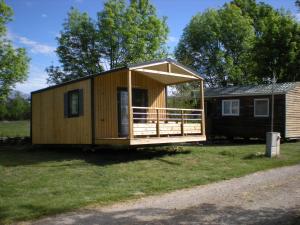 a large wooden cabin with a porch on the grass at Camping Las Asperas*** in Palau-de-Cerdagne