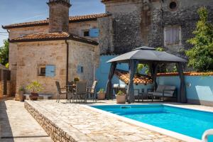 a pool in front of a house with an umbrella at Rustic villa Casa Tessa with outdoor pool in Tar in Tar