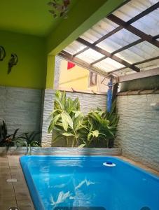 Cantinho feliz de Muriqui/ Casa verde com piscina privativa!!! في مانغاراتيبا: مسبح أزرق كبير في غرفة بها نباتات